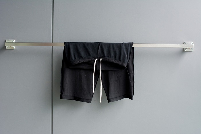 Swimming suit hanging on rack in bathroom.
