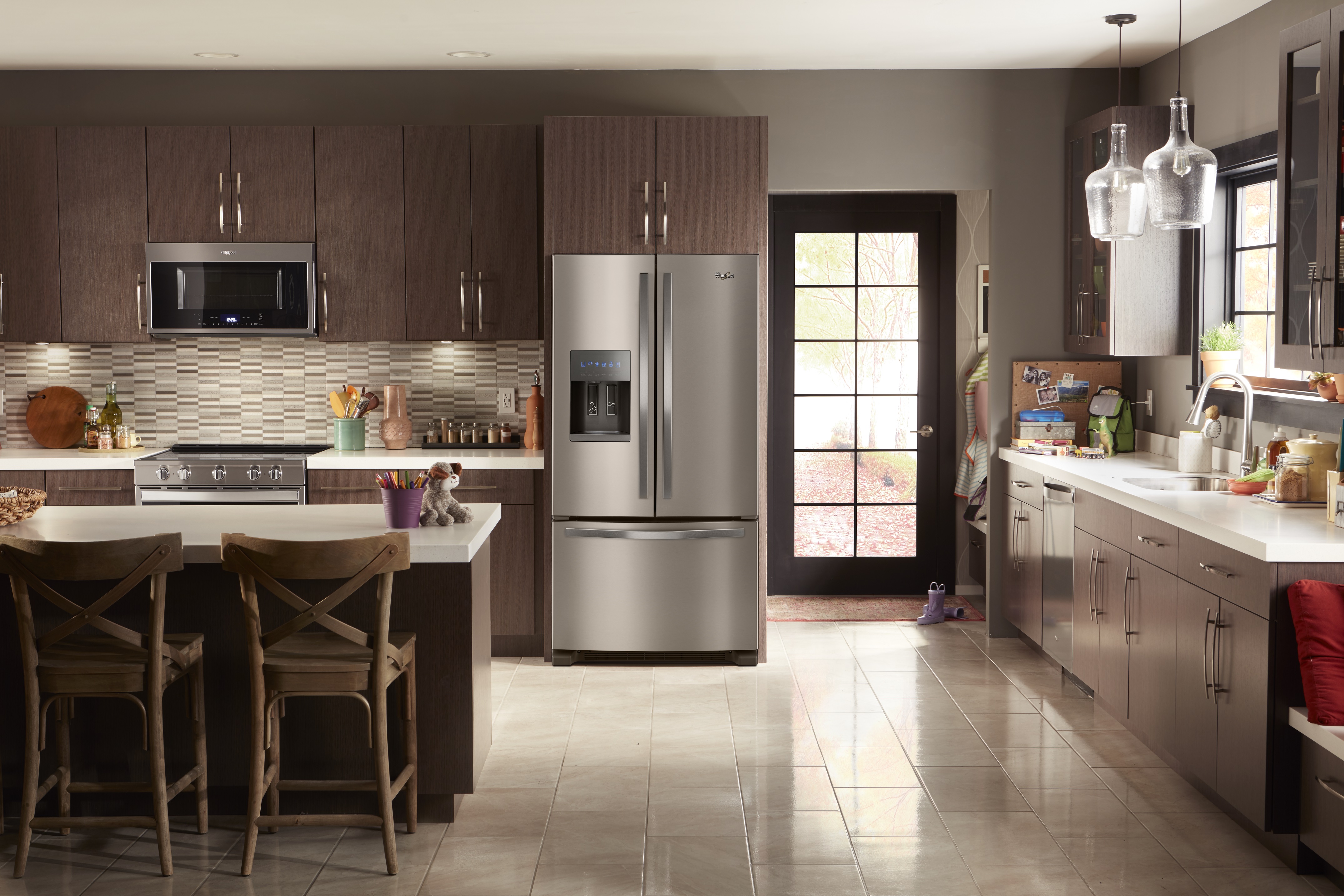 Whirlpool stainless steel French door refrigerator sits in sunlit kitchen