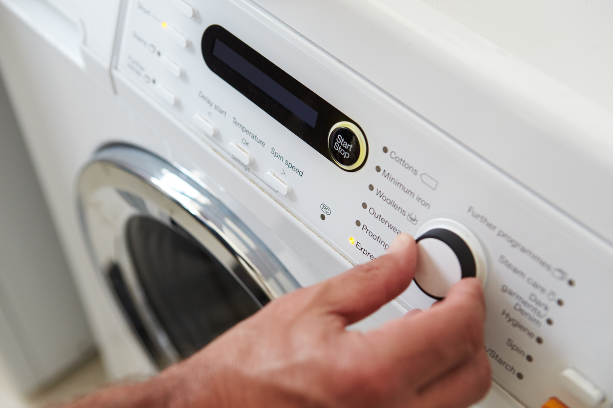 man choosing cycle program on washing machine