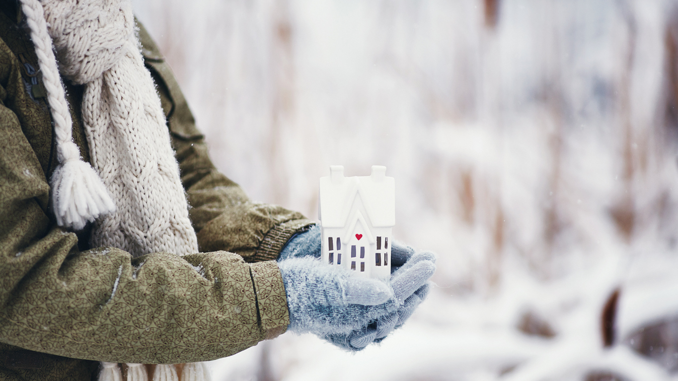outside, winter: mittened hands holding a ceramic house with a heart on it