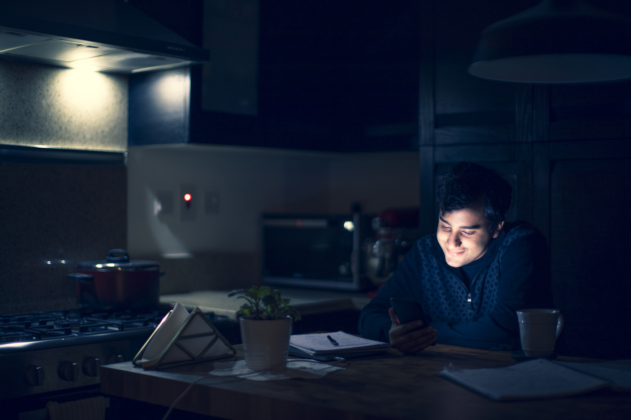 Young man taking a late night study break to be on his phone.