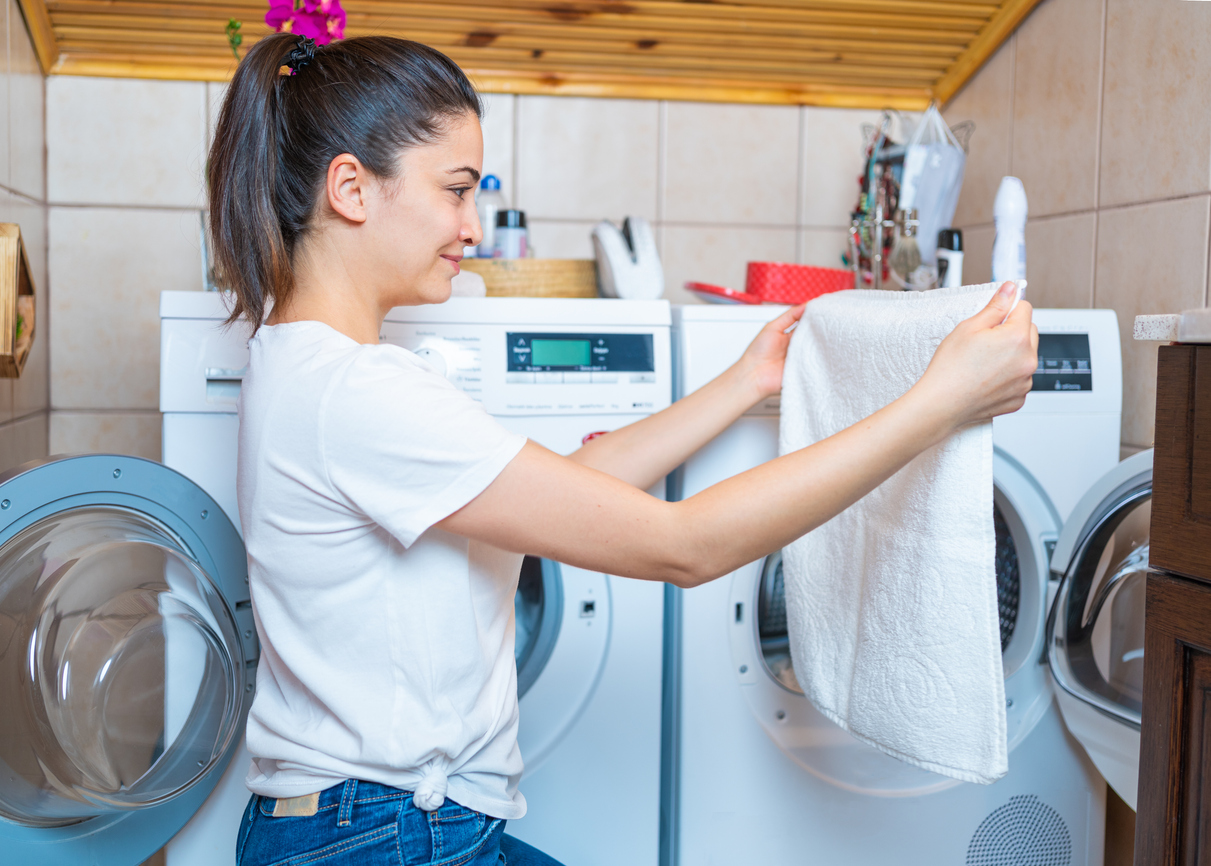 woman smiles as she takes clothes out of front-loading washer 