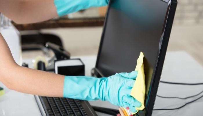 Someone dusting off computer monitor