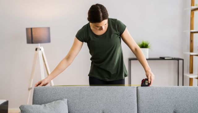 front view of a woman measuring the top of a sofa
