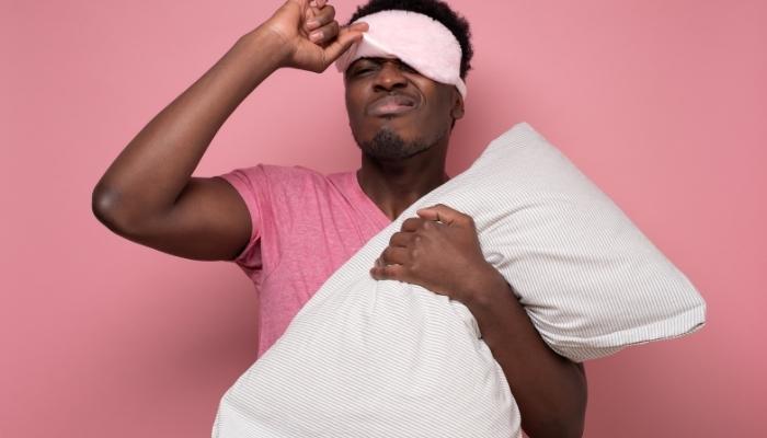 Man with sleep mask holding pillow