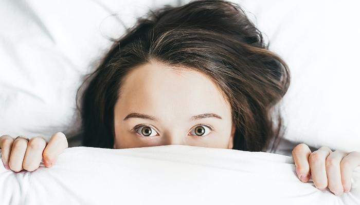 Woman holding sheet up to her face