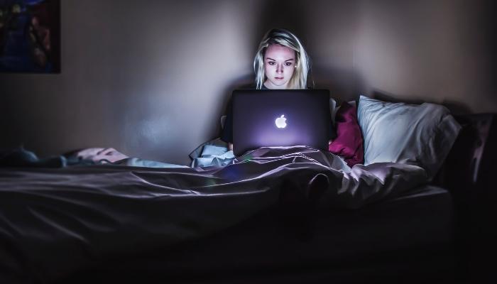 Woman staring at laptop screen while in bed