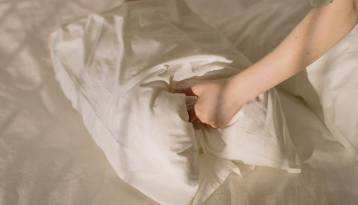 person putting on pillowcase