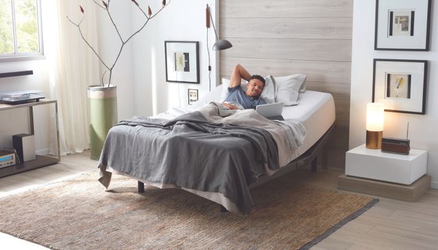 view of a man watching his laptop on an adjustable bed in a modern room