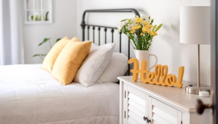 picture of nice bedroom with yellow pillows, flowers, and a hello sign