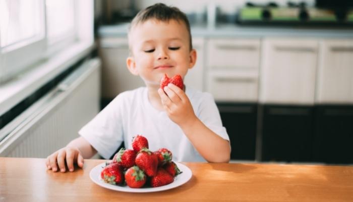 young child eating strawberries in the kitchen