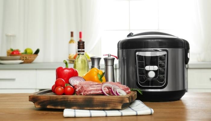 meat and vegetables on cutting board next to pressure cooker in kitchen