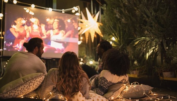 a group of friends watching a movie outside