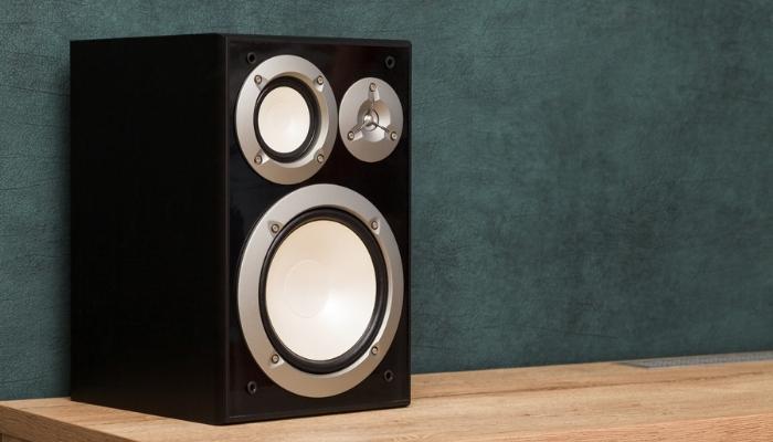subwoofer on wooden desk near dark green wall