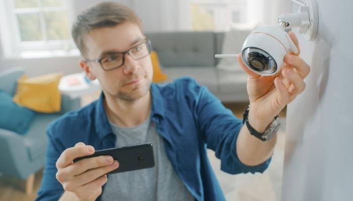man in glasses adjusts smart security camera at home