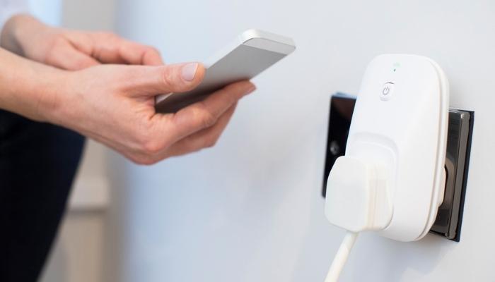 woman controlling smart plug using app on mobile phone 