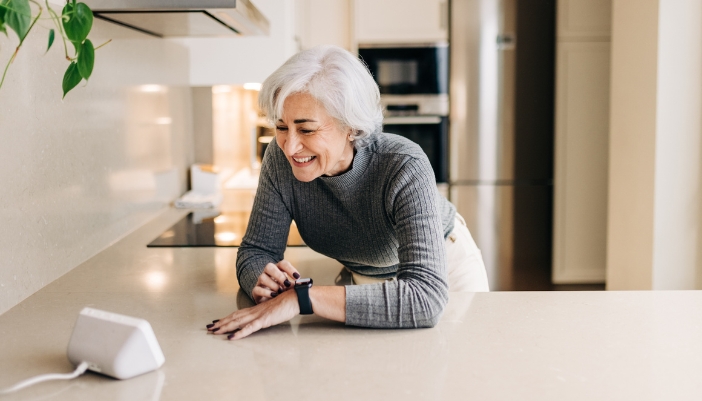 elderly woman talking to voice control in kitchen 