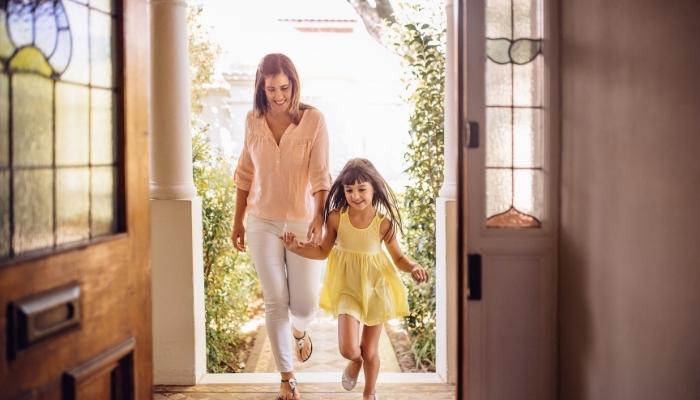 Mother and daughter coming through the door on a spring day