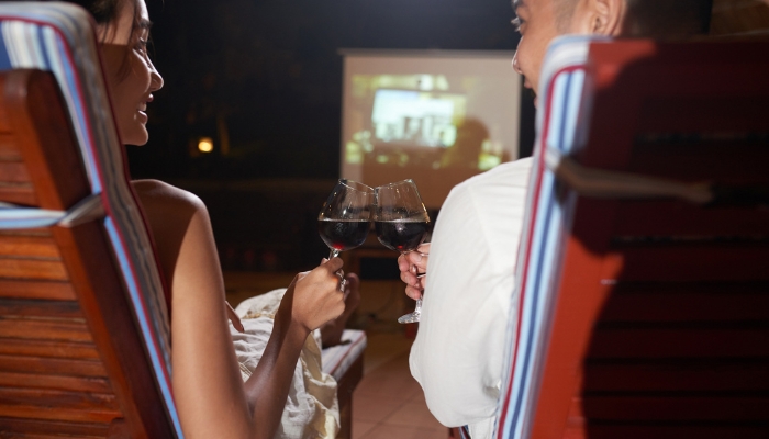 Couple toasting to each other as they watch something on backyard projector