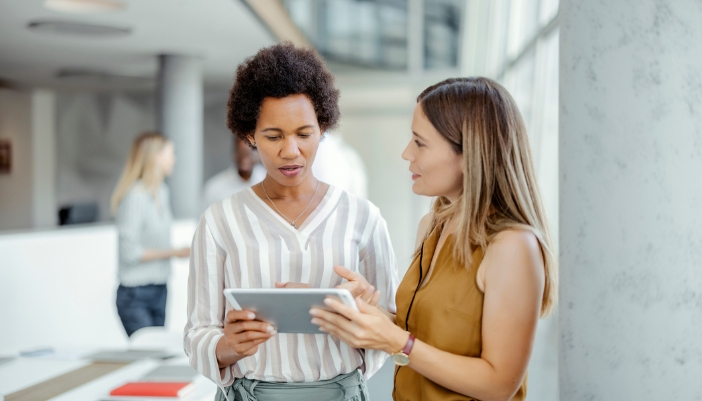 Two employees working, collaborating over a tablet connected to the business’ system