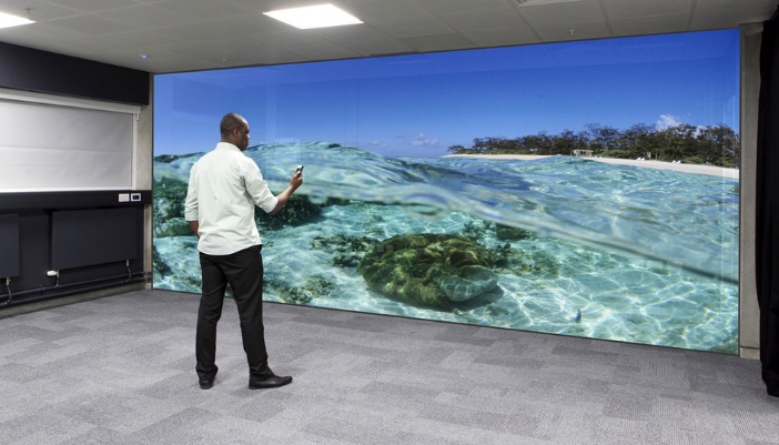 CI_Deciding-On-Video-Walls_2.jpg A person standing in front of video wall featuring a realistic ocean beach scene