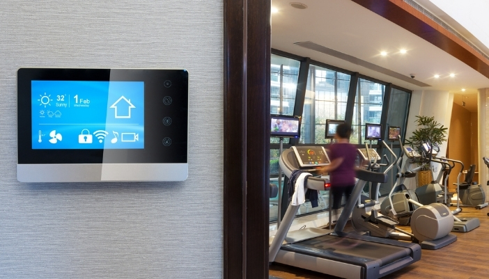 A closeup of someone working out in a modern home gym and the smart control panel in front of it