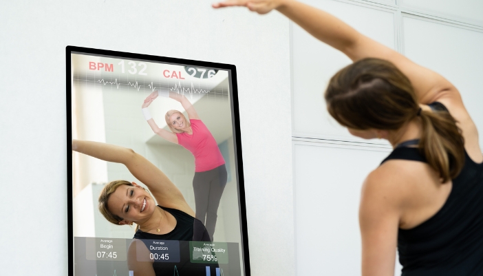 Woman doing exercise routine through a guided smart mirror routine