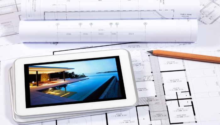House plans with a tablet showing a luxury home with outdoor lighting; planning the layout concept