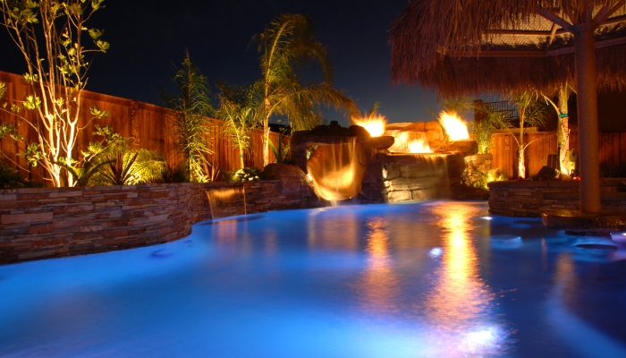 Luxury pool at night with dim lights and waterfall running