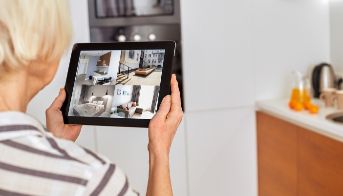 A senior woman monitoring home through her smart security cameras