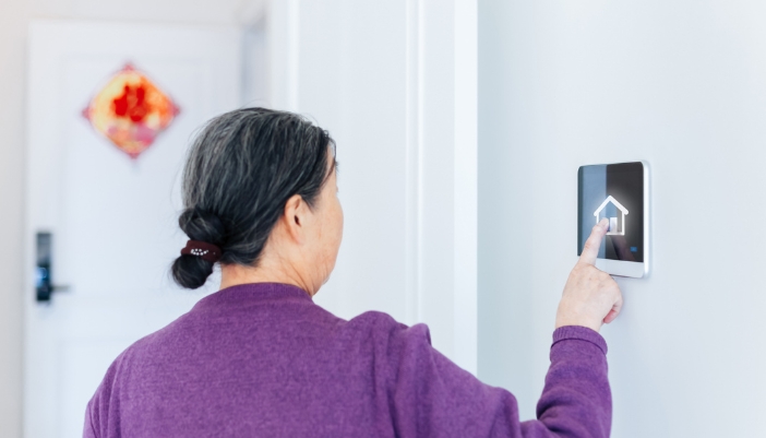 An elder woman using her smart panel to lock her home
