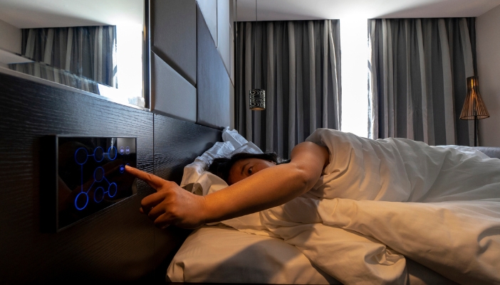 Woman using bedside controls to open hotel blinds