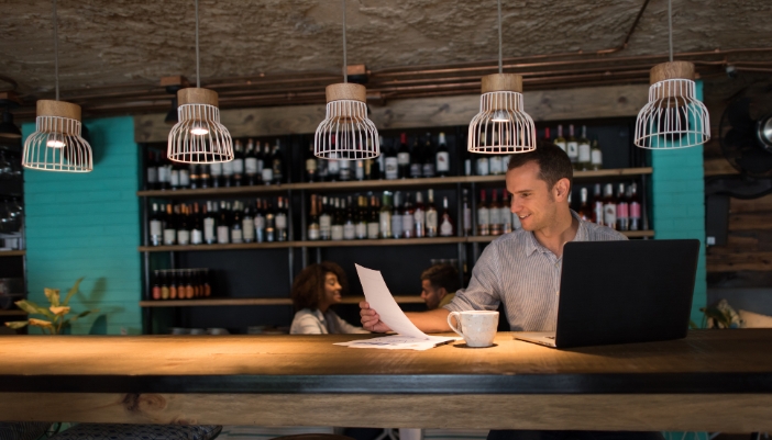 A bar with someone working on the counter peacefully and a couple having drinks in the background