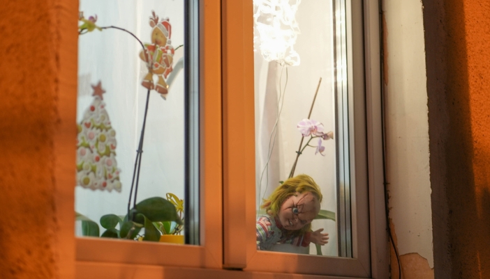 Concept image of a Chucky doll sitting in a window