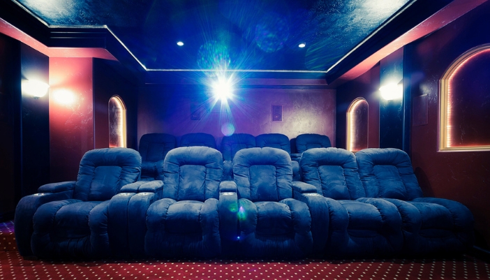 A home theater with a projector in a box behind the theater