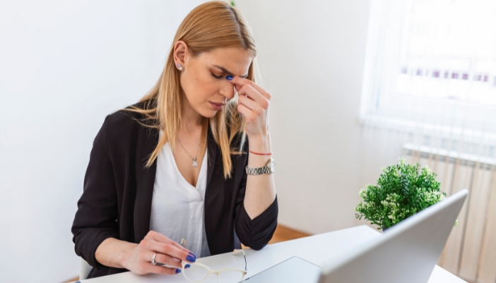 Woman closing her eyes because of eye strain from working in odd lighting