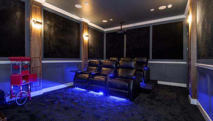 A home theater with luxury recliners and LED lighting and a popcorn carousel in the corner