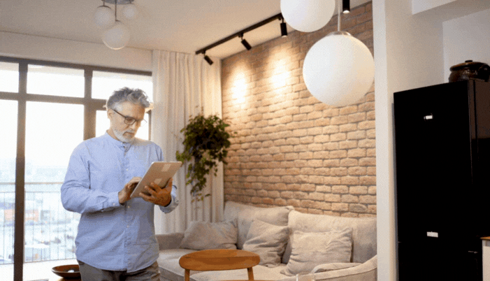A senior man using his tablet and app to turn on his living room lights
