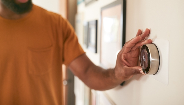 man adjusting smart thermostat