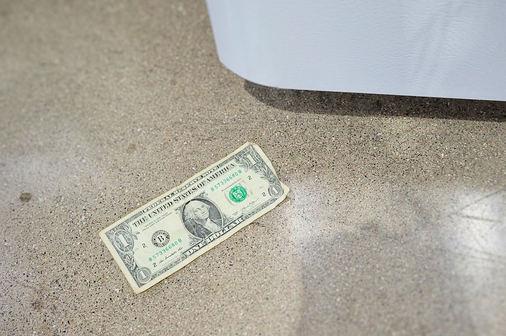 Dollar bill on the floor next to a refrigerator 