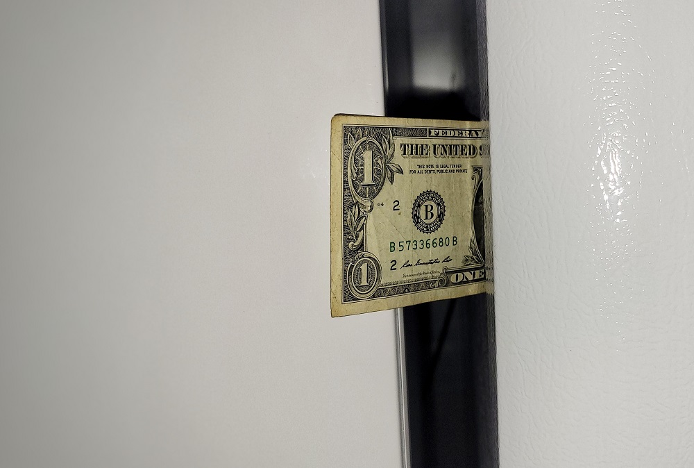 Dollar bill sticking out from refrigerator door 