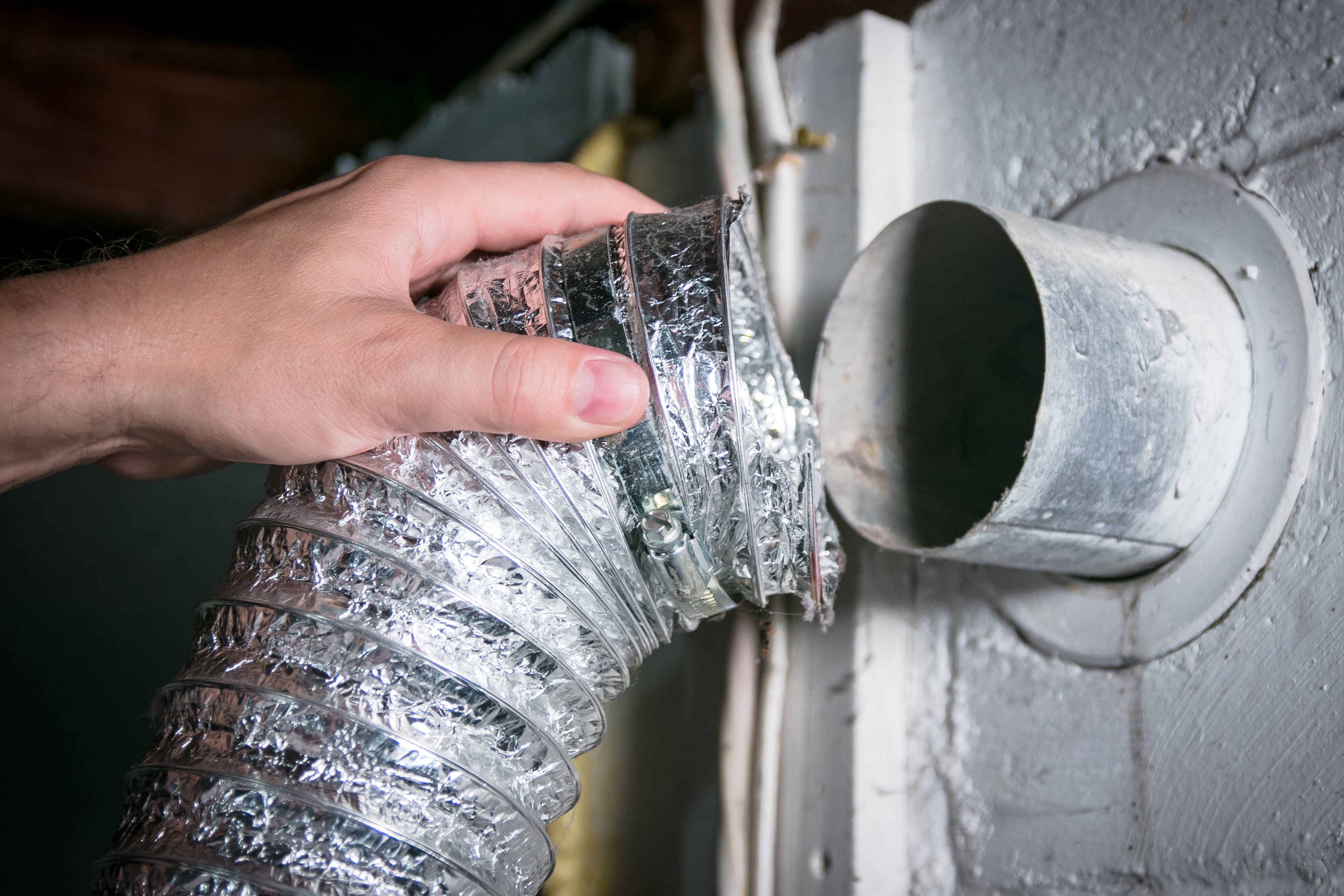 A person adjusting a dryer hose vent