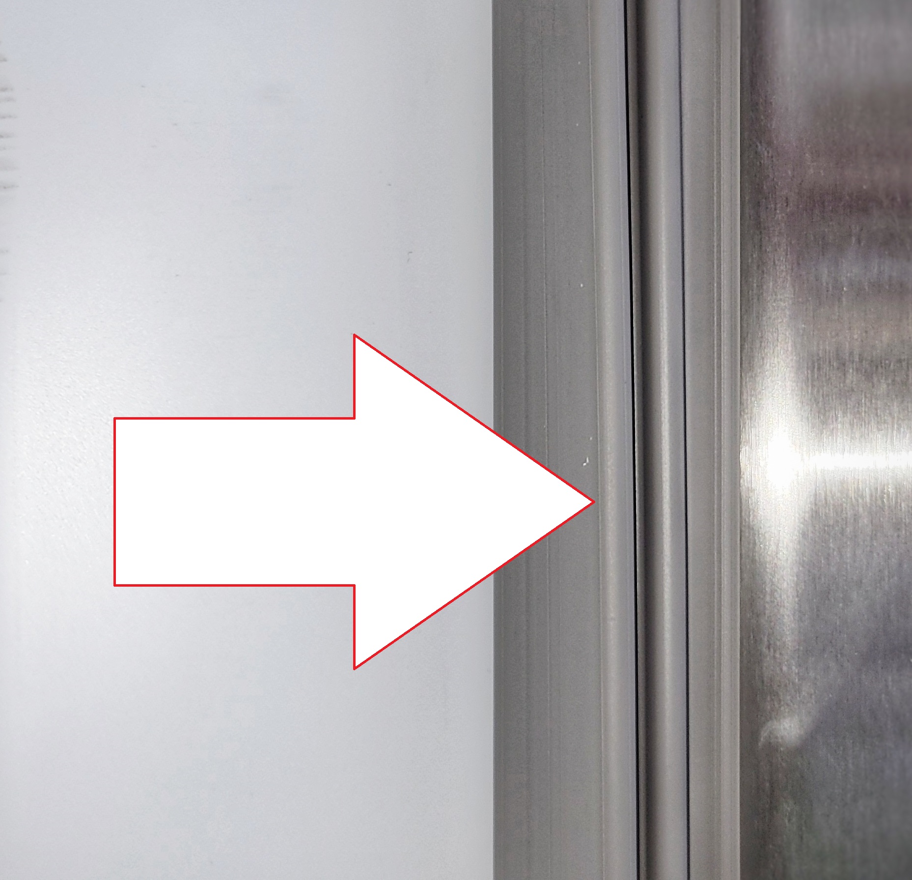 Graphic arrow pointing to inside refrigerator gasket