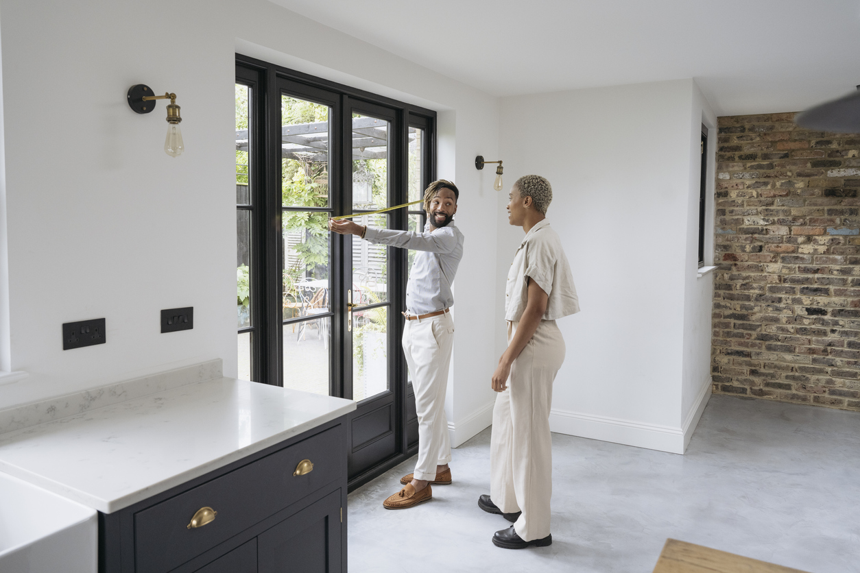 couple measuring width of doorway leading outside to patio