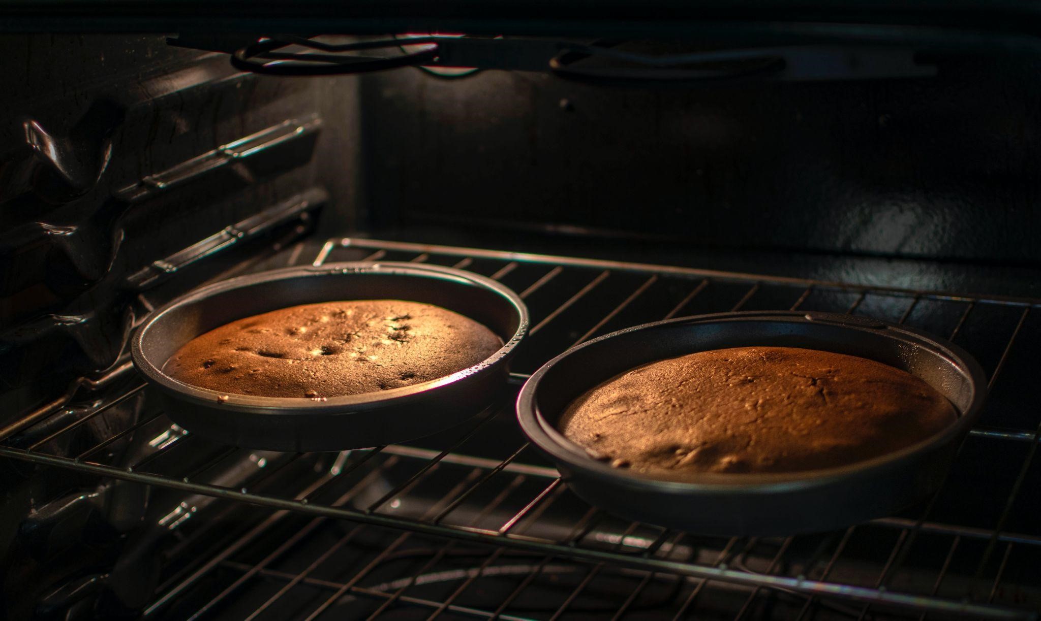 Two cakes baking side-by-side inside a convection oven 