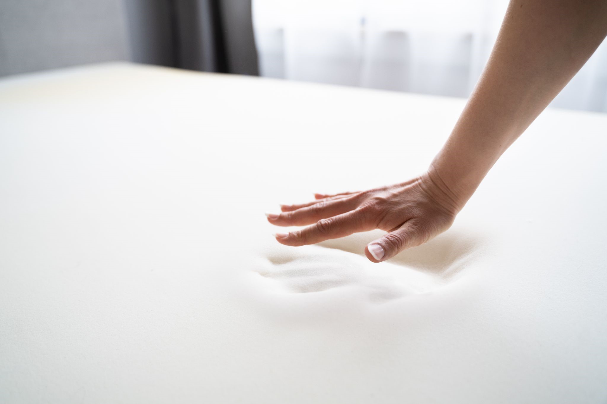 Person pressing down on memory foam mattress