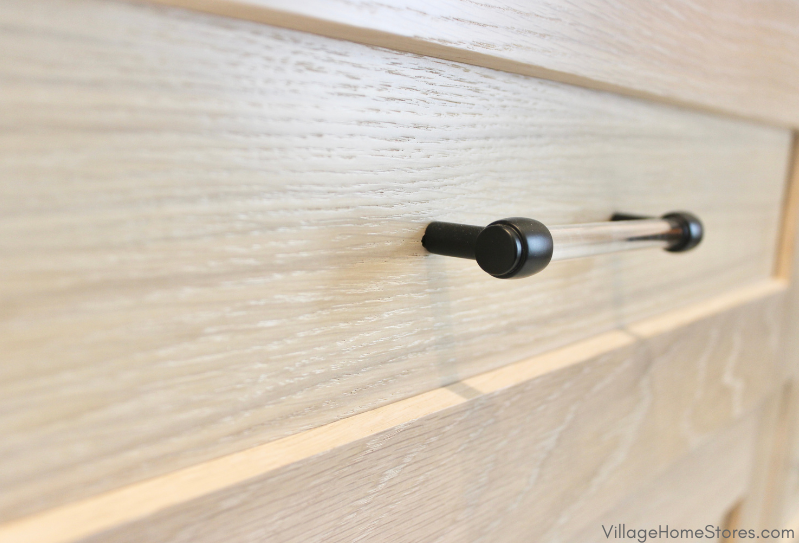 Close up of acrylic and black handle hardware on the drawer front of a white oak cabinet. Cabinetry and hardware by Village Home Stores.