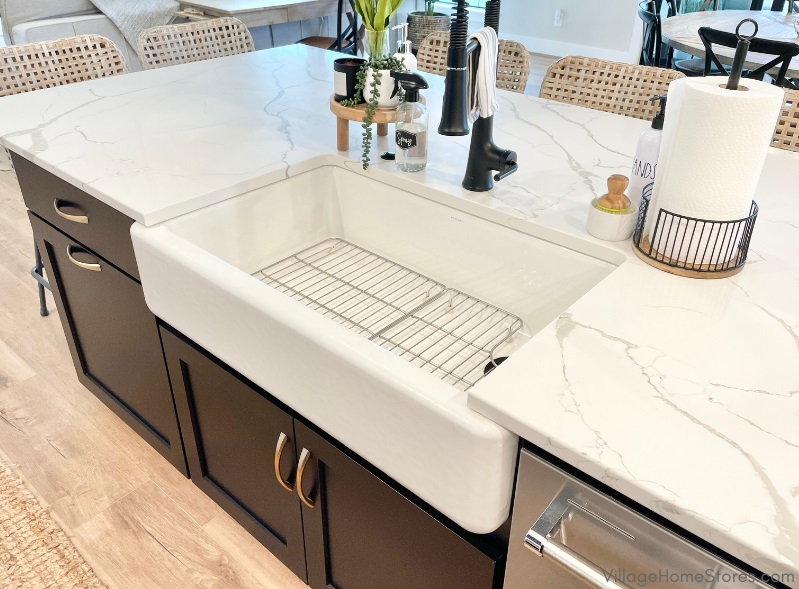 white farm sink installed in marble look quartz counters and black painted kitchen island. Kitchen cabinetry and tops by Village Home Stores for Bettendorf Iowa kitchen design.