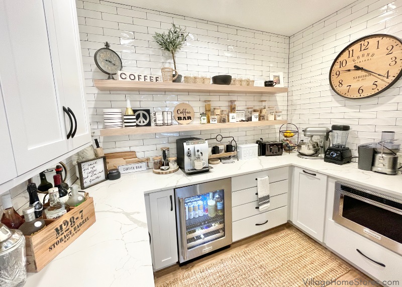 Open concept pantry and coffee bar design with white subway tile walls, white cabinets, and white oak floating shelves.
