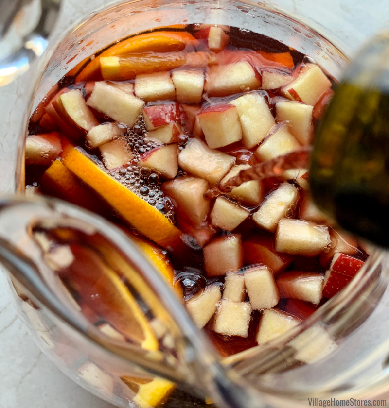 close up of sangria fruit in pitcher as red wine is poured into it